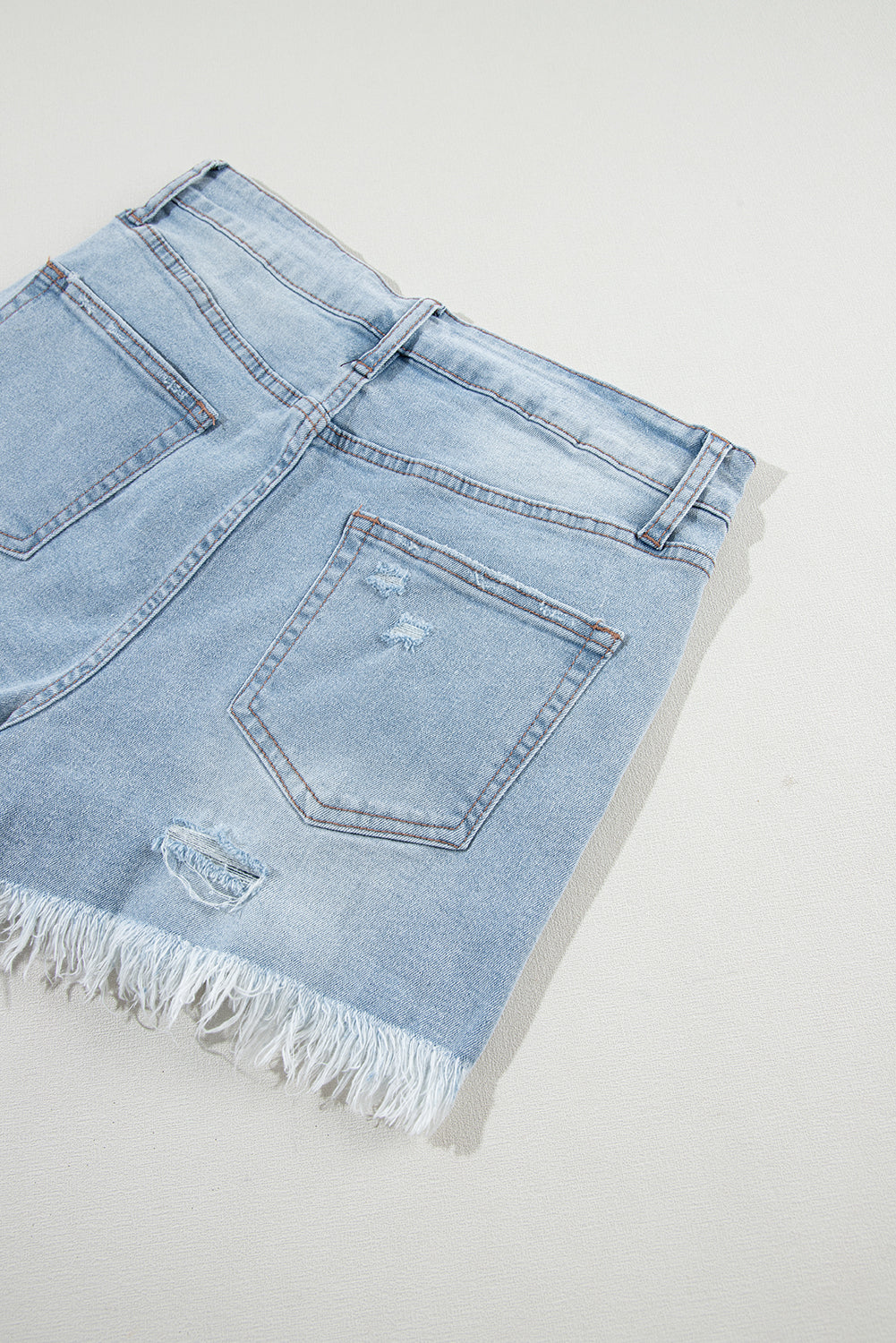 Shorts de denim azul claro desgastados con roturas, tiro alto y dobladillo crudo