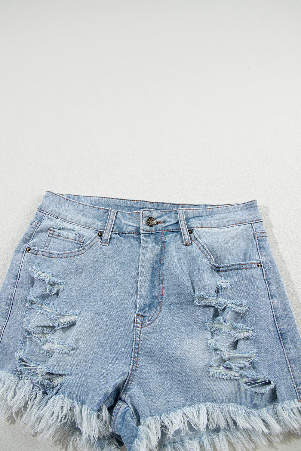 Shorts de denim azul claro desgastados con roturas, tiro alto y dobladillo crudo